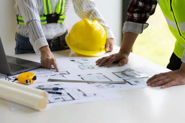 people looking at blueprint on table and planning with yellow helmet and ruler on table -general construction