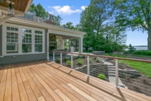 Modern wooden deck with cable railing, surrounded by greenery. -deck railing construction