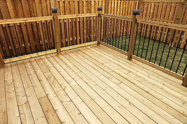 Wooden deck with a fenced perimeter, featuring vertical black balusters. -deck railing construction