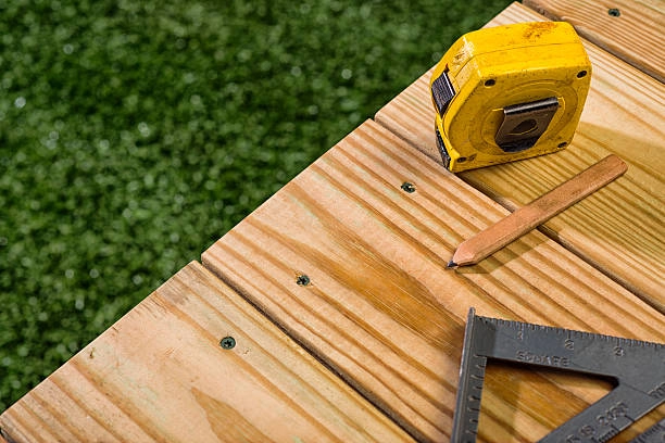 Close-up of deck construction tools: measuring tape, pencil, square. -deck construction guide