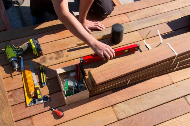 Worker assembling deck boards with tools, level, and measuring equipment. -deck installation