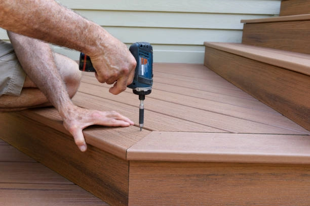 Person using a power drill to secure composite decking on stairs. -deck installation