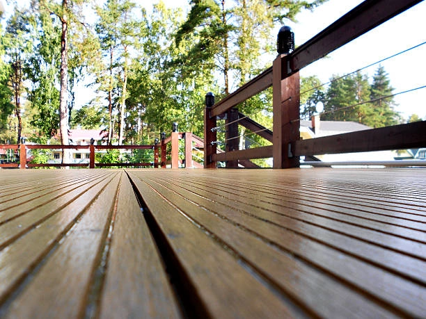 Wooden deck with modern railing, surrounded by trees and outdoor lighting. -decking wood