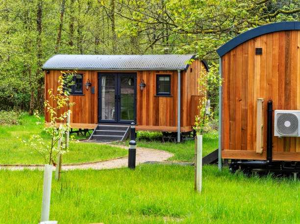 Wooden tiny homes with metal roofs set in a grassy woodland. -adu construction company