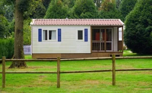 Small cottage with a red-tiled roof, porch, and blue shutters. -what does adu mean in construction