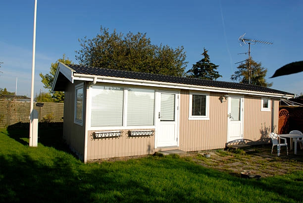 Beige single-story house with white trim, large windows, and patio chairs. -what does adu mean in construction