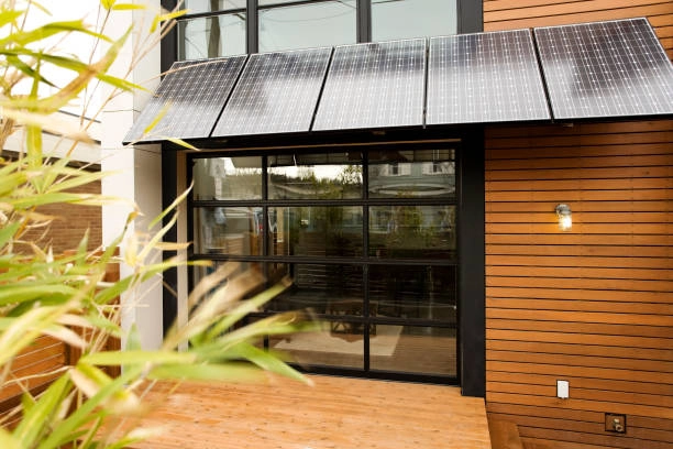 Contemporary building with solar panels above large glass doors and wood siding. -adu construction companies