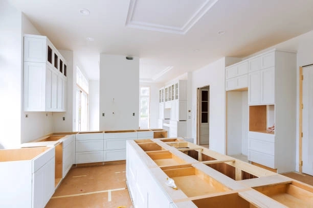 Modern kitchen under construction with white cabinetry and spacious layout. -general construction duties