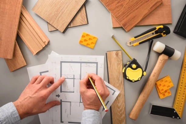 Design planning with floor plans, wood samples, and construction tools. -general construction duties