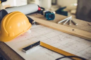 Construction workspace with blueprints, hard hat, tools, and measuring equipment. -what is general construction