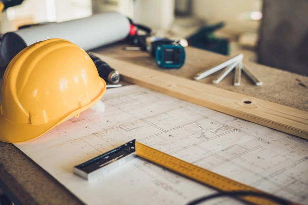 Construction workspace with blueprints, hard hat, tools, and measuring equipment. -what is general construction